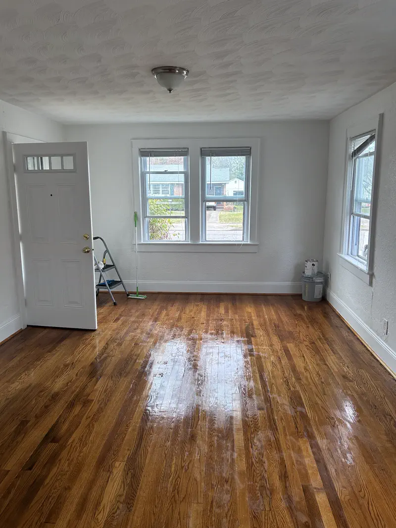 A bright empty room with a newly finished oak strip floor